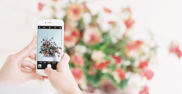 user taking a picture of flowers on her smartphone 