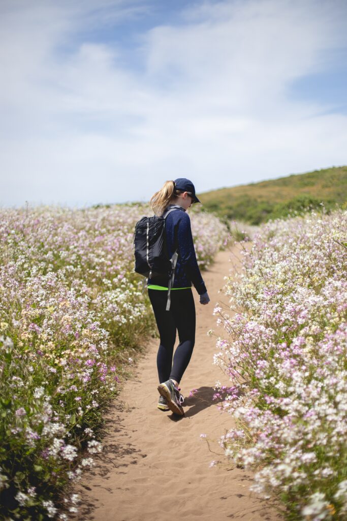 Girl taking a walk along a dirt road surrounded by meadows 