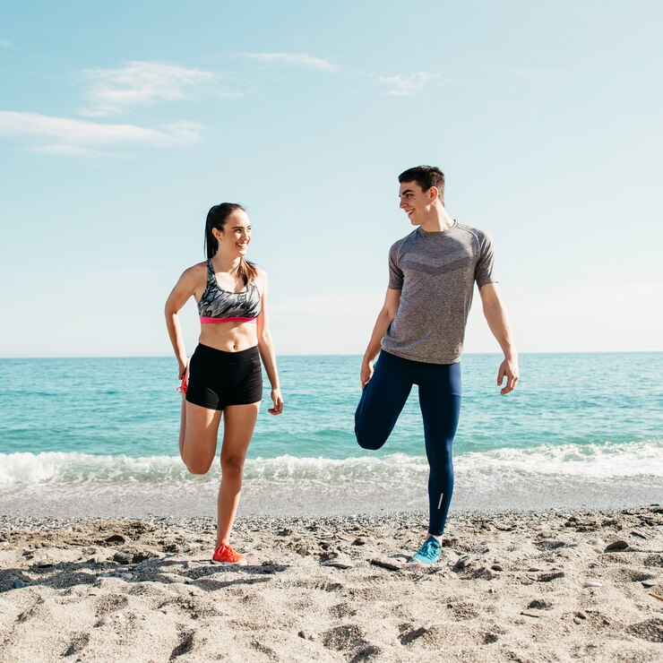 Couple stretching at the beach and smiling