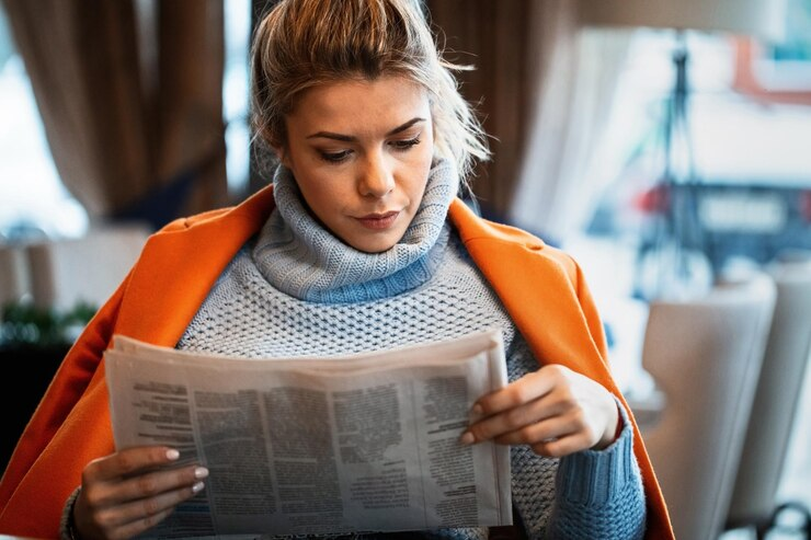 Woman reading a newspaper with deep concentration